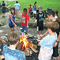 Teens roasting marshmallows around a campfire