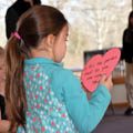 young girl holding heart paper cut out