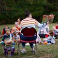 adult reading book to group of children outside