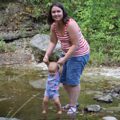 mom and baby daughter holding hands in creek