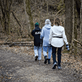 three people walking a trail through the woods in winter