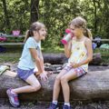 two girls sitting on log at fire circle