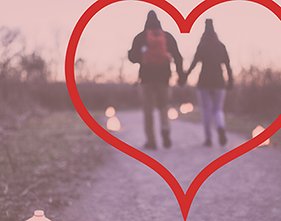 heart overlaid on photo of couple holding hands on trail with luminaries