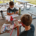 two boys drawing and coloring at a picnic table