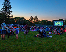 crowd surrounding outdoor movie screen at sunset, Forest Field Park