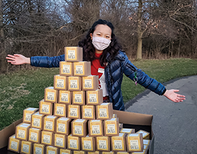 volunteer standing behind a stack of small boxes