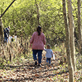 mom and daughter walking down a wooded trail