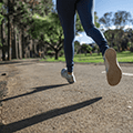 shot of a woman's feet running on a paved trail through a park