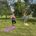two woman doing yoga outside in a park