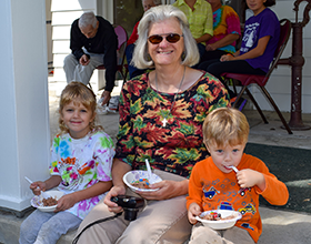 woman and two children sitting on a porch eating ice cream