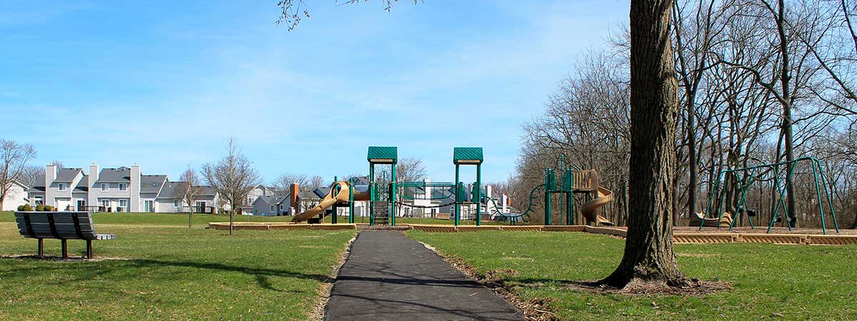 sidewalk leading up to a playground and a bench