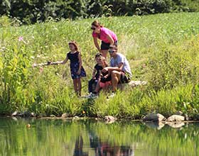 Family of five fishing at the edge of a pond