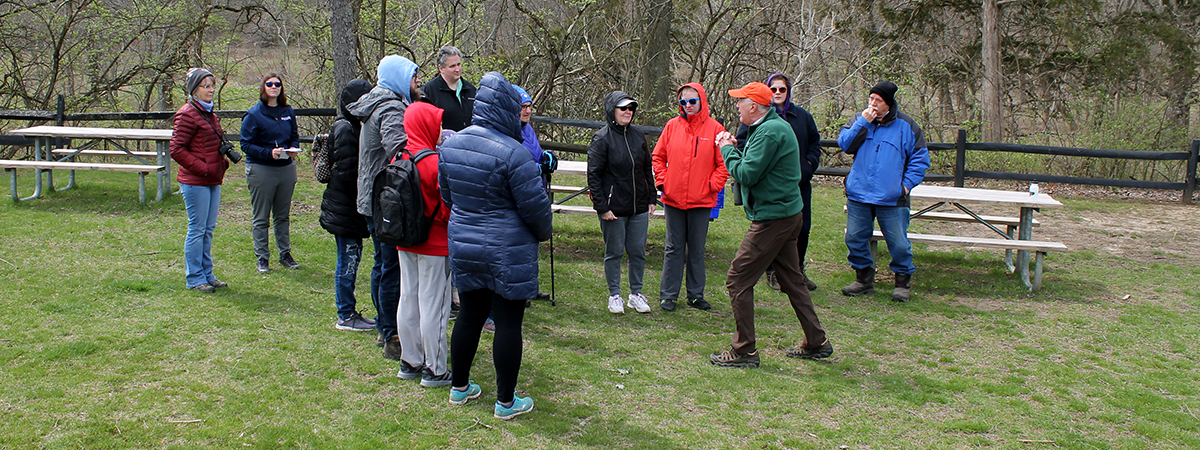 A group of adults standing in a green open area wearing winter gear.