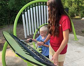 Teenager and child at outdoor musical instruments